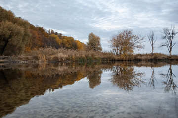 Serenity by the river, peaceful autumn nature with cloudy sky reflected in Ukraine