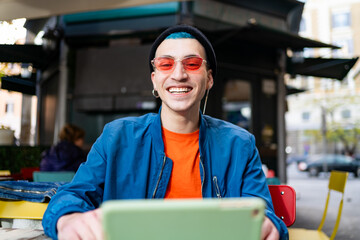 Stylish young man adjusting sunglasses at cafe