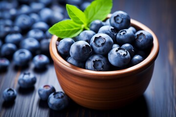 Heaped fresh blueberries in a wooden bowl with leaves on a dark wooden table