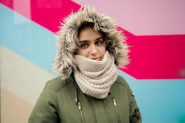 Young woman in cozy winter clothing with colorful background