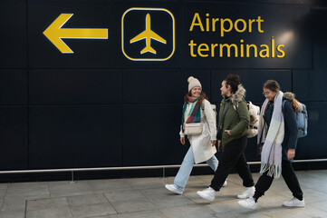 Travelers Walking by Airport Terminal Signage