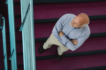 Senior businessman standing on steps at top of stairs looking up