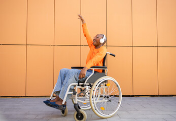 Joyful woman in wheelchair reaching upwards outdoors