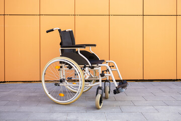 Modern wheelchair against orange wall