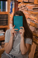 Woman Hiding Face With Book in a Library