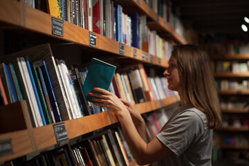 Woman Browsing Bookshelves in a Library