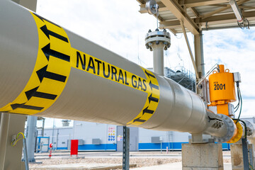 High pressure natural gas pipeline with direction sign at compressor station. Concept of energy...