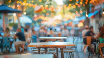 An empty table sits at an outdoor cafe in the daytime. The cafe is filled with people, and the background is blurred to create a sense of movement and activity.