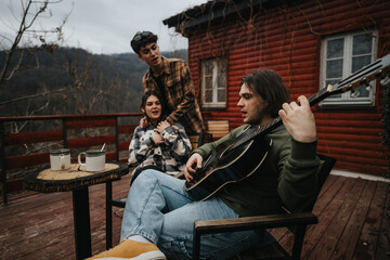 Couple enjoys a serene moment with guitar music on a rustic cabin porch surrounded by forest