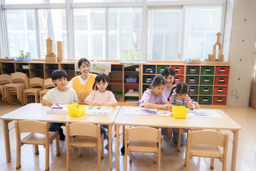 学童や放課後デイサービス等で勉強をする先生と生徒　小学生複数の広角