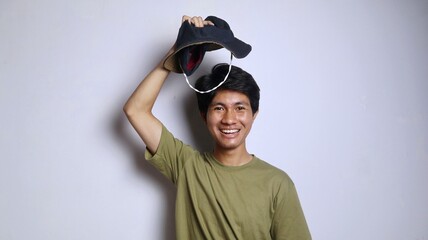 young asian man holding a hat