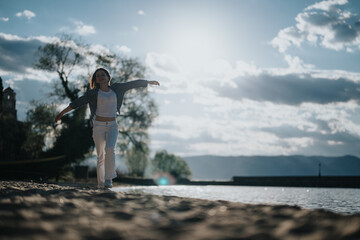 Capturing a moment of pure joy, this image features a woman balancing and walking along a lake...