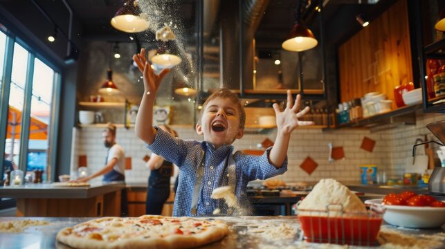 A young boy is having fun in a kitchen while making pizza. He has flour all over his face and hands as he throws some in the air.