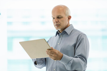 Senior manager reading news on tablet in office building