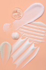 Samples of face cream on coral background, top view