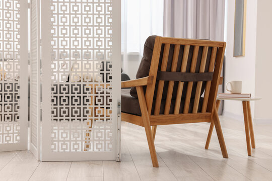 White folding screen, armchair and wooden table in living room