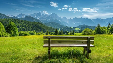 Rustic bench in a grassy meadow, green forest and majestic mountains under a bright blue sky, peaceful and inviting scene, plenty of copyspace