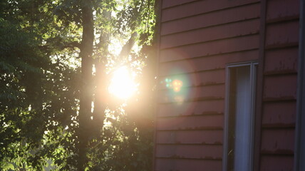 Sun Peaking through trees around an old red house