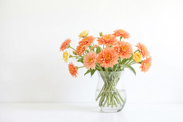 Peach-colored flowers in a glass vase on a white background