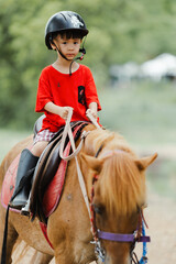 Portrait of Asia boy riding horse in the farm