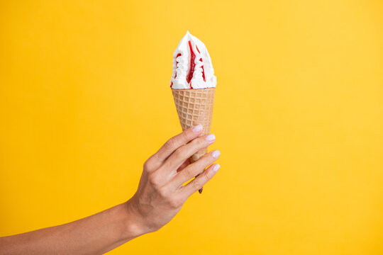 Gelato ice cream cone. Ice cream cone isolated on yellow. Summer vanilla taste. Woman holding the ice cream by hand. Ice cream in hand. Yummy summer gelato. Authentic Italian gelato