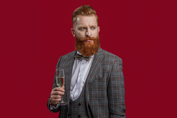 Elegant tuxedo man hold glass of champagne isolated on red. Celebrating success. Cheers. Bearded man with formal look. Celebrate with champagne. Cheering and celebrating. Celebrate anniversary