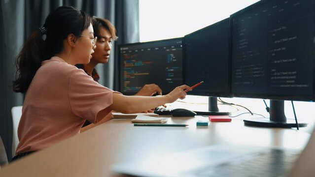 Slow motion back end software developer engineer for computer programming working together on debugging writing computing code, solving complex algorithms display on monitor in office. Burgeoning