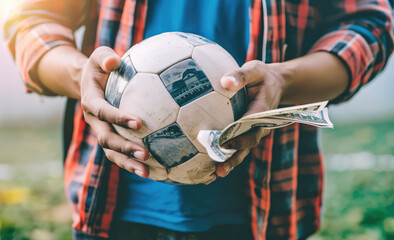 Obraz premium Closeup of hands holding money and a small soccer ball, representing the concept of gambling on sports events