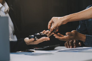 Car sales representative gives keys to new car owner, concept for car rental Focus on the key. Pick up the key. Close-up of the key transfer from the new machine to the buyer.