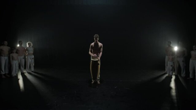 Bare-chested drummer playing the conga on stage under spotlight. Focused on rhythmic beats, showcasing skill and intensity. Cultural performance with traditional percussion
