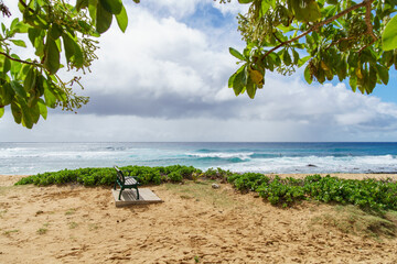 A bench is placed on a sandy beach overlooking the ocean under the expansive sky