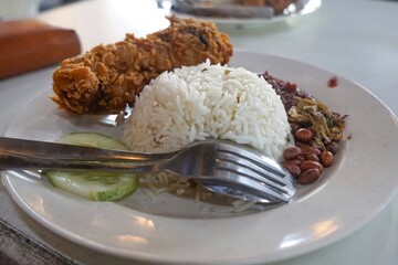 Nasi lemak, a Malay style complete meal of fragrant rice cooked in coconut milk and eaten together with chili paste, fried chicken, hard boiled egg, anchovies and cucumber.