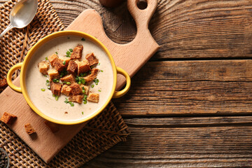 Pot of tasty cream soup with croutons on wooden background