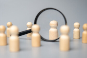Obraz premium Wooden dolls and magnifying glass. Talent acquisition, recruitment and hiring concept.