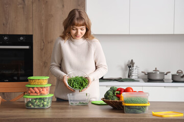 Woman pouring green beans in plastic container for freezing in kitchen