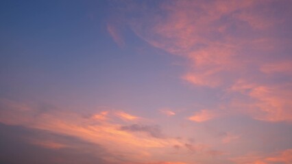 A beautiful sunset with a sky painted in soft pink and orange hues. The clouds are gently dispersed across the sky, creating a tranquil and serene atmosphere. Cloud background.
