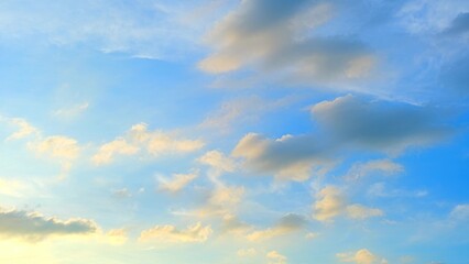 A clear blue sky adorned with soft, fluffy clouds. The light creates a beautiful gradient in the sky, enhancing the serene and tranquil atmosphere. Nature's beauty background.
