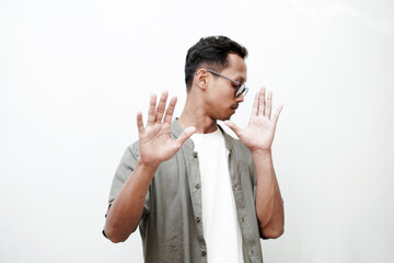 a young man wearing a plain shirt and wearing glasses with a dismissive expression (raises both hands). With a plain white background