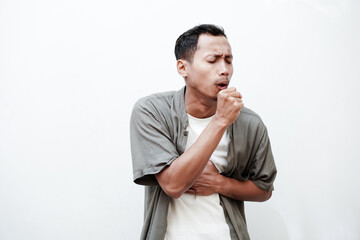 a young man wearing a plain shirt, having a cough, flu with one hand holding his chest. With a plain white background