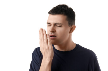Handsome young man feeling bad smell on white background