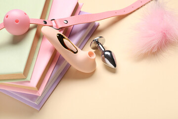 Different sex toys and books on beige background, closeup