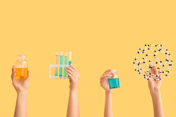 Female hands holding filled test tubes with bottles and molecular model on yellow background....