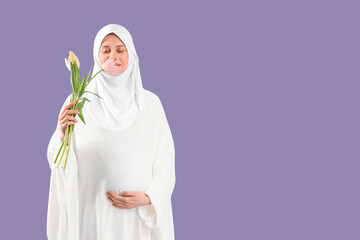 Pregnant Muslim woman with tulips on lilac background