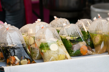 A table with several plastic bags of food, including carrots and potatoes