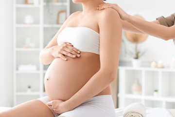 Young pregnant woman having massage in spa salon, closeup