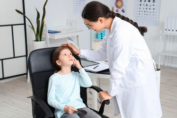 Obraz premium Female ophthalmologist examining little girl's eyes in clinic