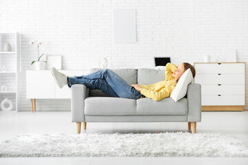 Young happy woman sleeping on sofa in living room