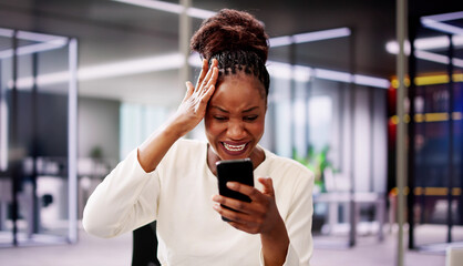 Worried African American woman staring at broken smartphone in office