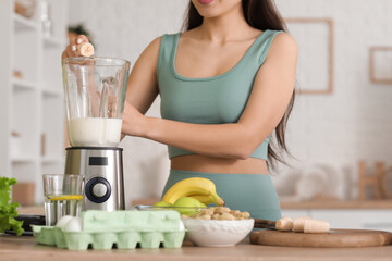 Sporty young Asian woman making protein shake at home, closeup