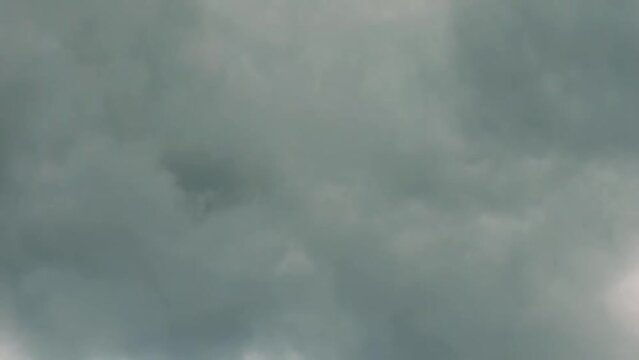 Timelapse video capturing the rapid movement of dark rain clouds across the sky. The accelerated motion emphasizes the dynamic and changing weather patterns, offering a dramatic view of nature power.